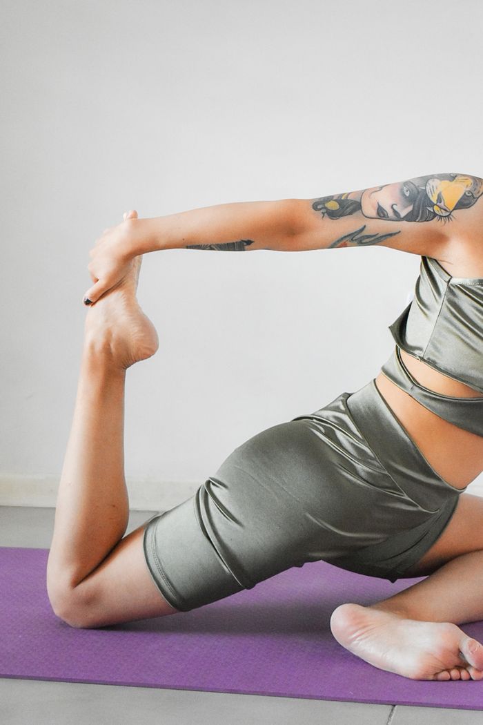 Home Female athlete in sportswear practicing a stretching pose on a yoga mat.